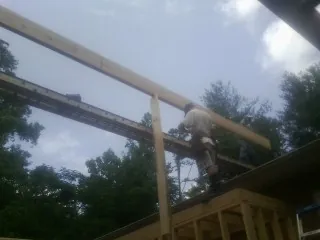 Carpenter setting a ridge beam over a new addition frame — Ice Dam Removal by Roofing Brothers in New Plymouth