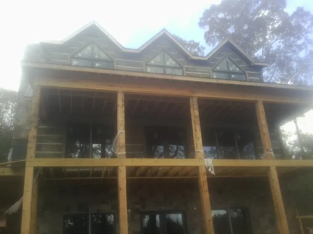 Dormers and porch framing on a large log home under construction — Roof Coating work by our crew in New Plymouth